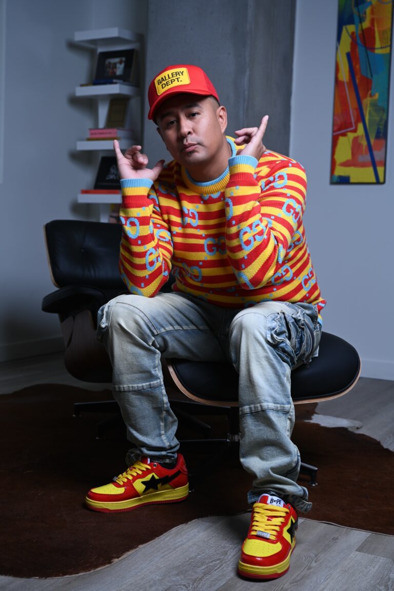 Randy L. Barton, Dine artist, seated in a lounge chair wearing a red cap and a red and yellow striped sweater.