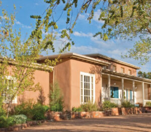 Territorial style home in Santa Fe with brick coping and white-trimmed windows