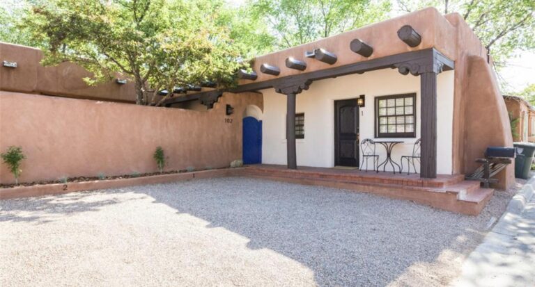Gravel courtyard with a blue door and a covered portal at the 102 Pena Place compound, Santa Fe