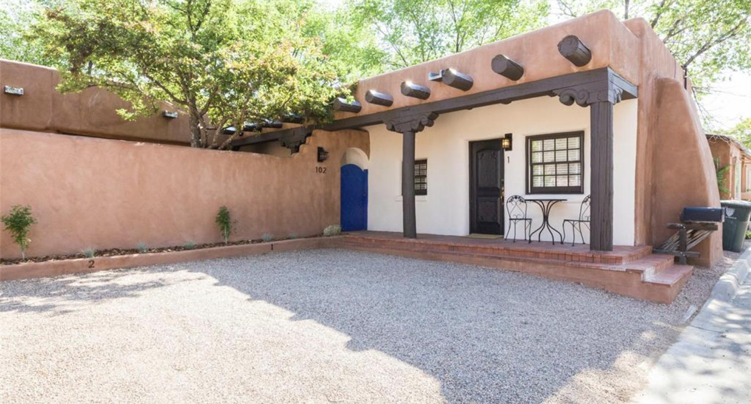 Gravel courtyard with a blue door and a covered portal at the 102 Pena Place compound, Santa Fe
