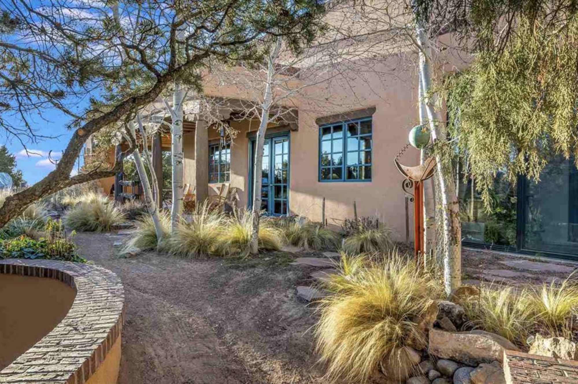 Adobe exterior with divided light windows and native grass landscaping at 1104 Bishops Lodge, Santa Fe