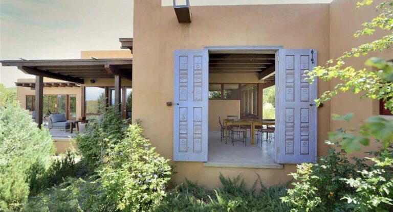 Carved blue shutters open onto a dining portal at Casa La Vega, 1801 Camino de la Cruz Blanca, Santa Fe