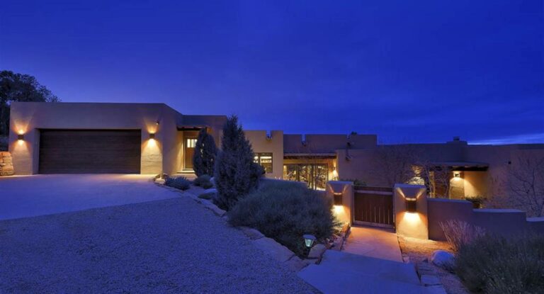 Contemporary house lit at dusk with gated entry and garage at 1862 Camino Cruz Blanca, Ponderosa Ridge, Santa Fe