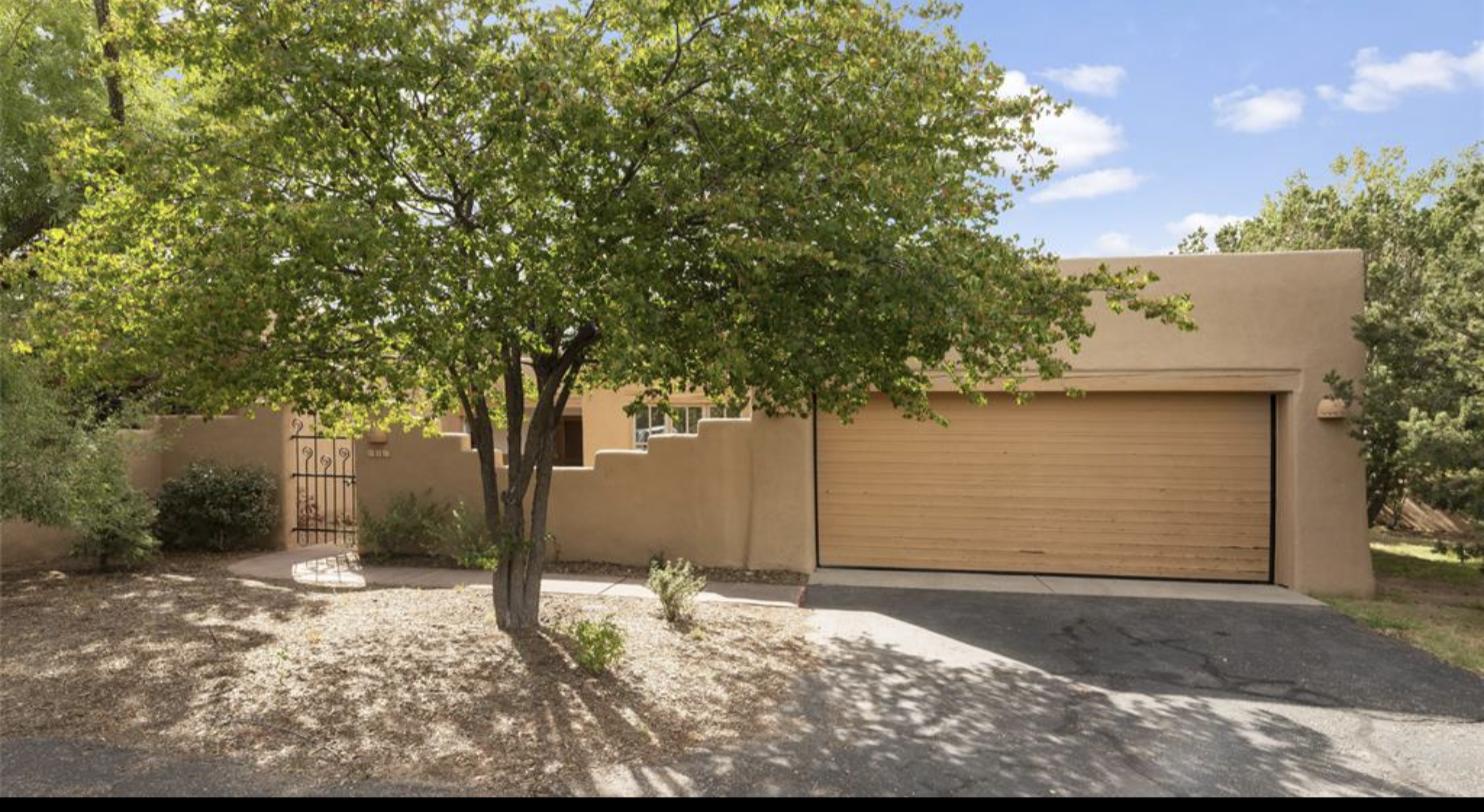 Adobe exterior with a mature tree and attached garage at 3101 Old Pecos #686, Quail Run, Santa Fe