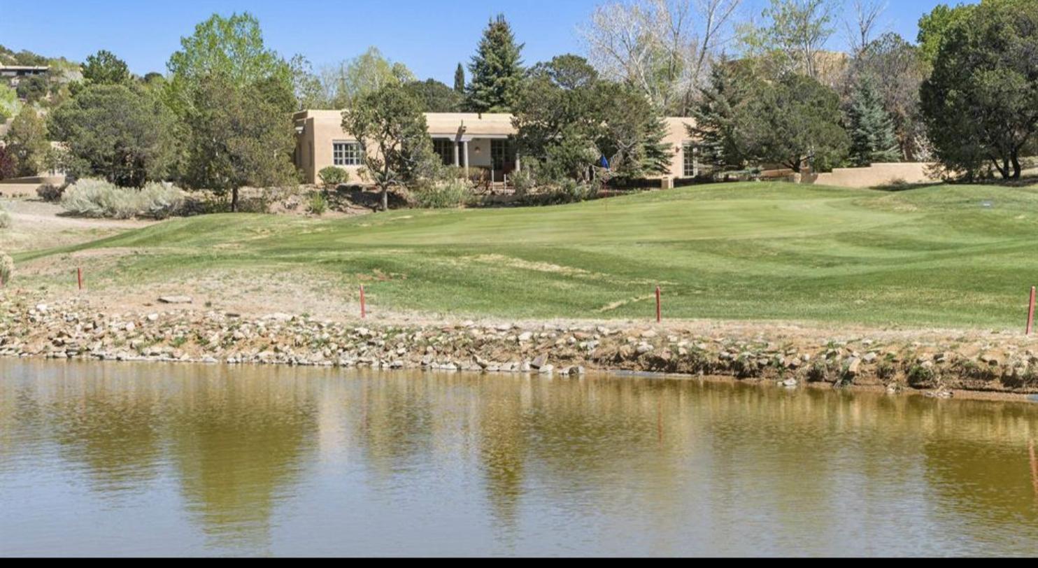 The hacienda at 3101 Old Pecos Trail #612 seen across the first fairway and pond at Quail Run, Santa Fe