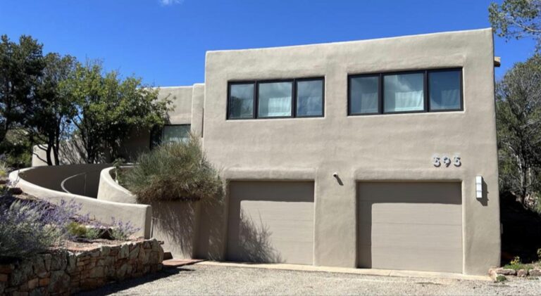 Adobe exterior with clerestory windows and a curved stucco wall at 393 Calle Colina, Santa Fe