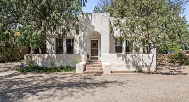 White adobe facade with an arched entry and divided light windows at 524 Garcia Street, Santa Fe