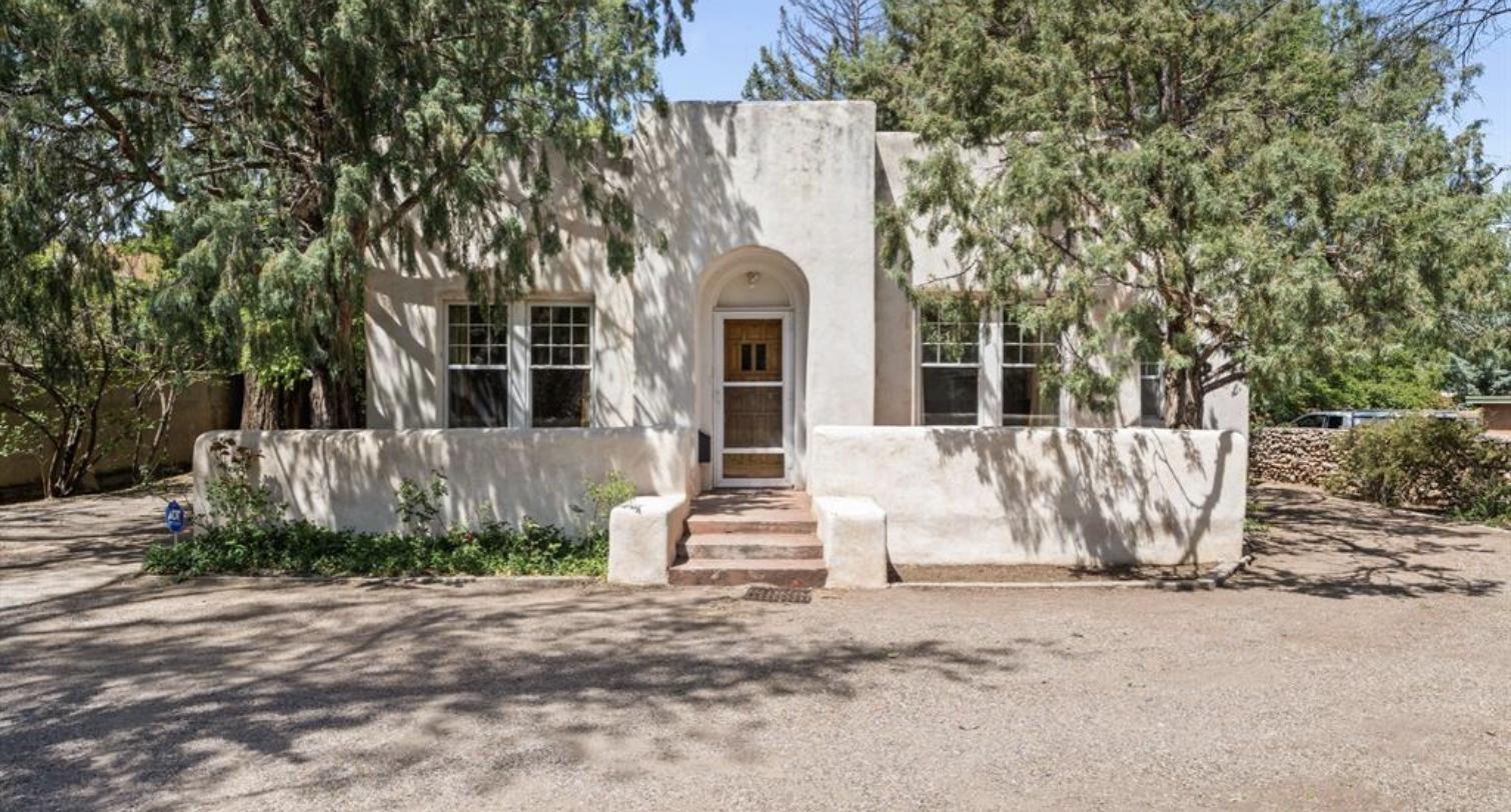 White adobe facade with an arched entry and divided light windows at 524 Garcia Street, Santa Fe