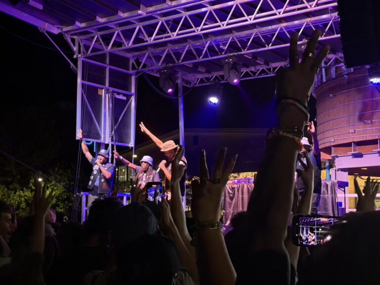 Souls of Mischief performing under purple stage lights with the crowd's hands raised at Raashan Ahmad's Hip Hop Festival, Santa Fe Railyard Plaza, August 2026.