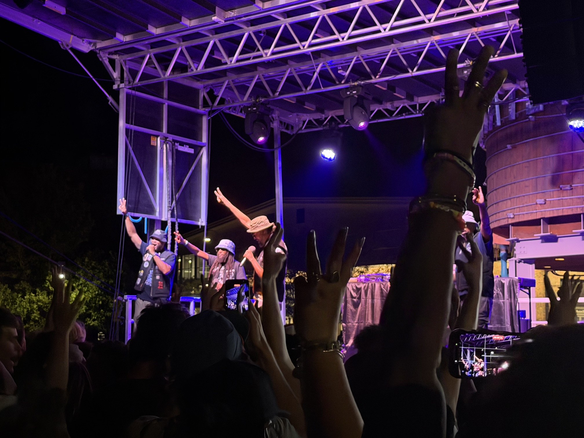 Souls of Mischief performing under purple stage lights with the crowd's hands raised at Raashan Ahmad's Hip Hop Festival, Santa Fe Railyard Plaza, August 2026.
